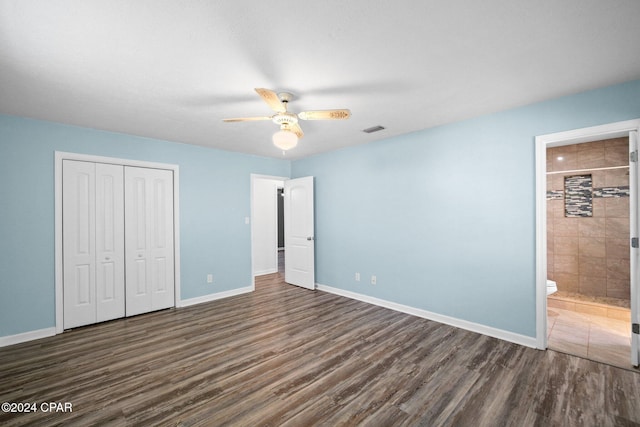 unfurnished bedroom featuring dark wood-type flooring, ensuite bathroom, a closet, and ceiling fan