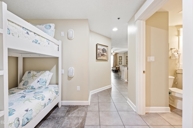 bedroom with light tile floors and ensuite bathroom