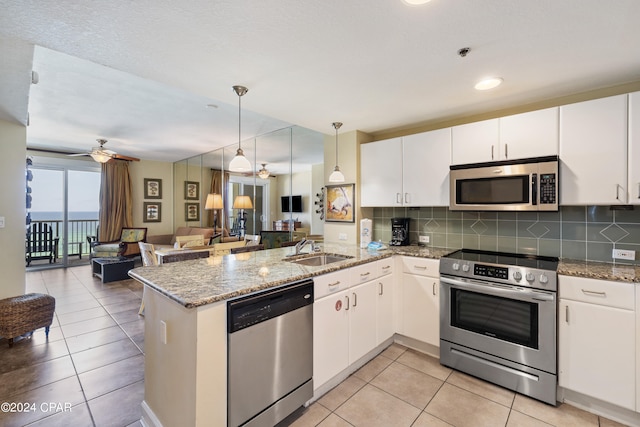 kitchen featuring kitchen peninsula, hanging light fixtures, ceiling fan, stainless steel appliances, and tasteful backsplash