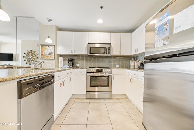 kitchen with decorative light fixtures, white cabinets, appliances with stainless steel finishes, light tile floors, and sink