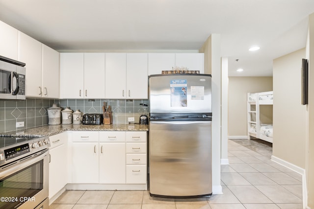 kitchen featuring light stone counters, appliances with stainless steel finishes, light tile floors, tasteful backsplash, and white cabinetry