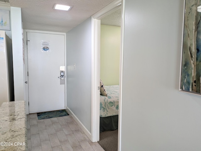 foyer entrance featuring a textured ceiling and baseboards