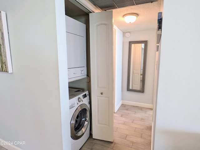 clothes washing area featuring laundry area, baseboards, visible vents, and stacked washer / drying machine