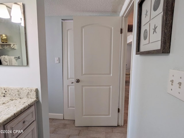 bathroom featuring a textured ceiling, vanity, and tile patterned floors