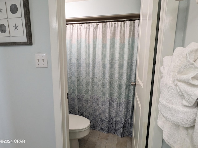 full bath featuring curtained shower, toilet, and wood finished floors