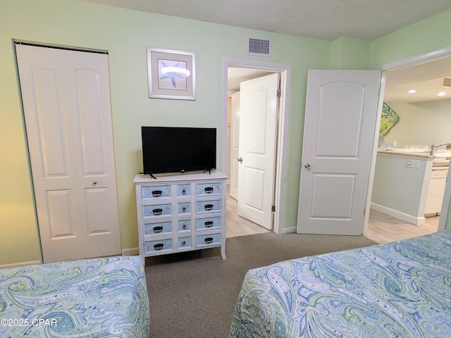 bedroom featuring baseboards, visible vents, ensuite bathroom, a textured ceiling, and a closet