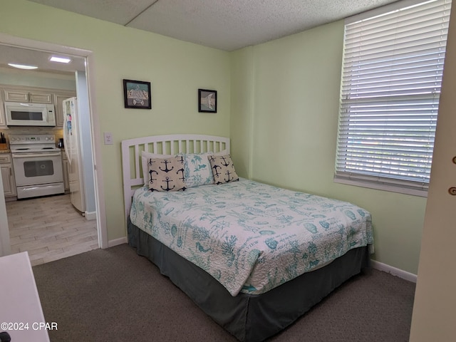 carpeted bedroom featuring white refrigerator and a textured ceiling