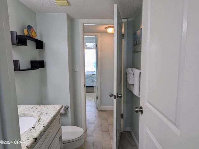 bathroom featuring wood finish floors, toilet, ensuite bathroom, a textured ceiling, and vanity