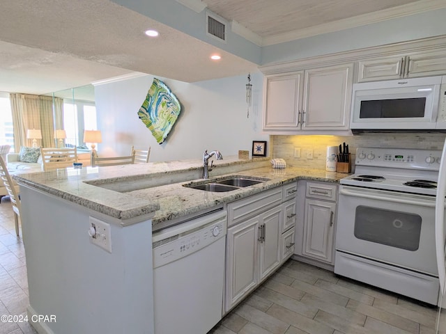 kitchen featuring ornamental molding, a peninsula, white appliances, and a sink