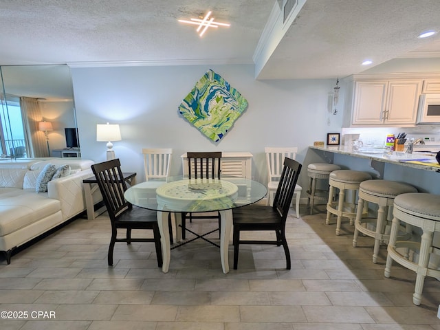 dining space featuring a textured ceiling, recessed lighting, and crown molding