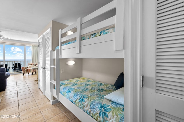 tiled bedroom featuring access to outside and a water view