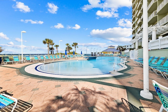 view of pool featuring a water view and a patio area