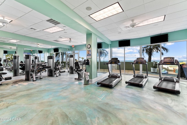 exercise room with ceiling fan, a paneled ceiling, and a wealth of natural light