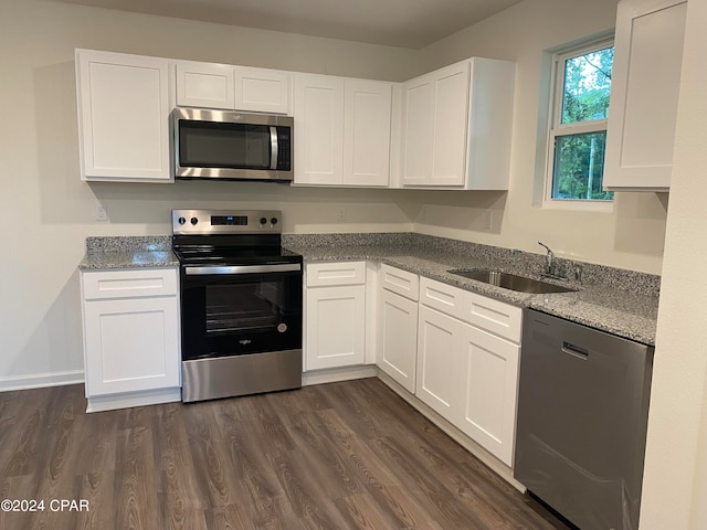 kitchen with light stone countertops, stainless steel appliances, white cabinetry, sink, and dark wood-type flooring