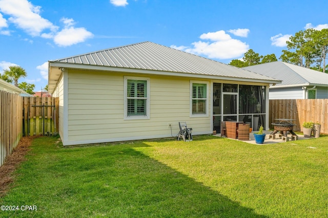 back of house featuring a fire pit, a lawn, a sunroom, and a patio area