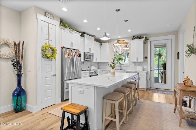 kitchen with a kitchen island, backsplash, stainless steel appliances, white cabinetry, and light wood-type flooring