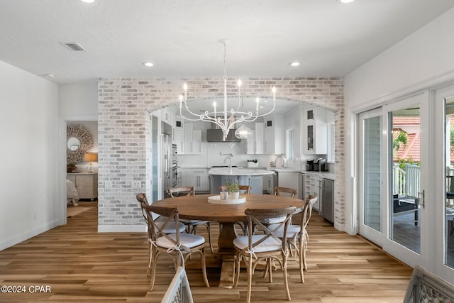 dining space featuring a notable chandelier, sink, and light hardwood / wood-style floors