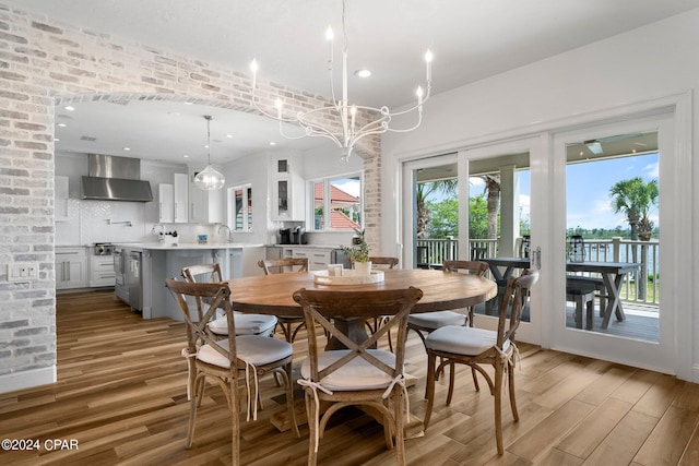 dining space with a healthy amount of sunlight, a notable chandelier, and light hardwood / wood-style flooring