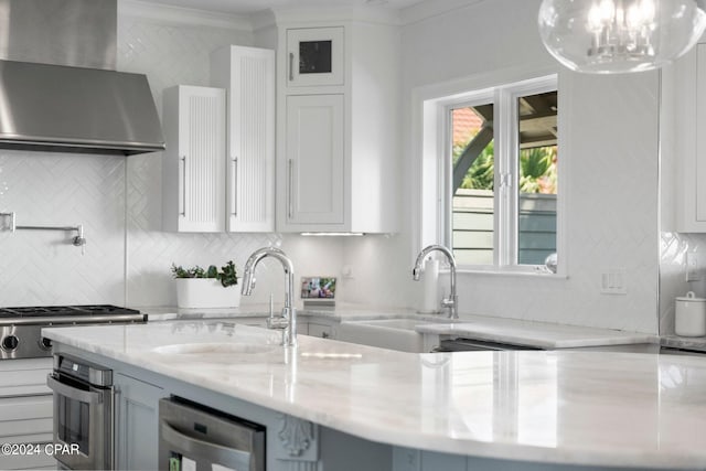 kitchen with crown molding, light stone countertops, wall chimney exhaust hood, oven, and tasteful backsplash