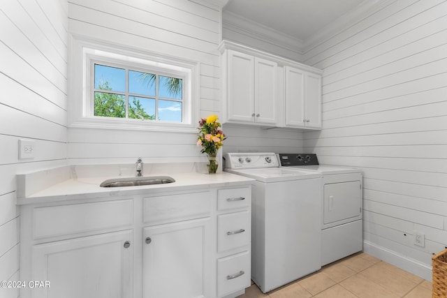 clothes washing area with wood walls, cabinets, washer and clothes dryer, and light tile floors