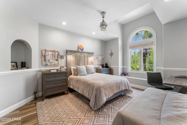 bedroom featuring wood-type flooring, lofted ceiling, ceiling fan, and multiple windows