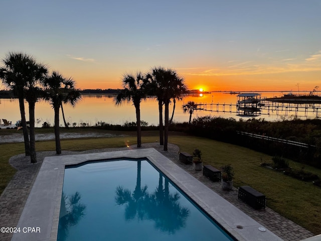 pool at dusk with a yard and a water view