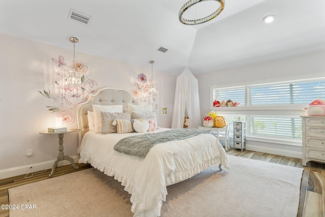 bedroom featuring a notable chandelier, hardwood / wood-style floors, and lofted ceiling