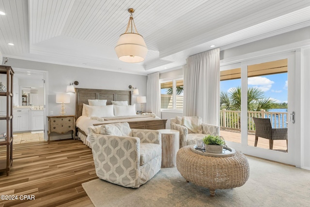 bedroom featuring access to exterior, a tray ceiling, hardwood / wood-style floors, and connected bathroom