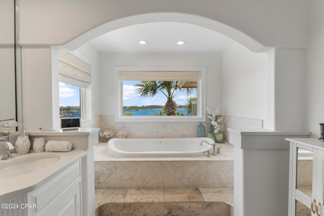 bathroom featuring tiled bath and vanity