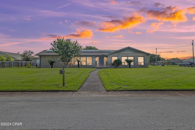 view of front of home featuring solar panels and a yard