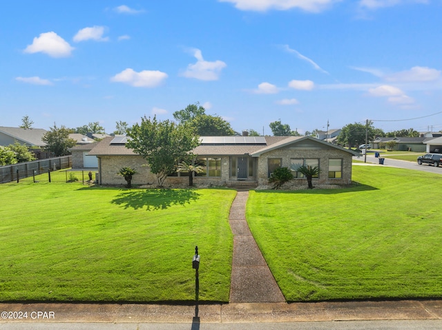 view of front facade featuring solar panels and a front yard