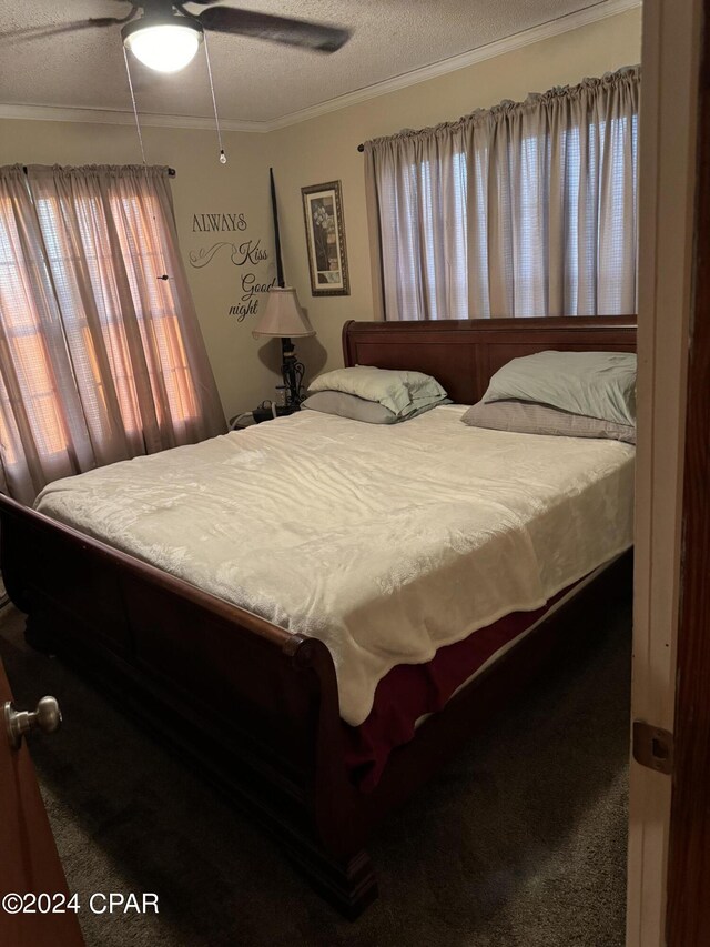 bedroom featuring ceiling fan, carpet, a textured ceiling, and ornamental molding