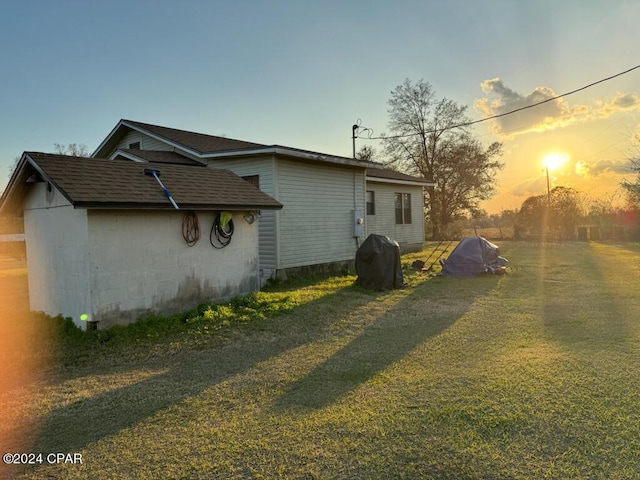 property exterior at dusk featuring a lawn