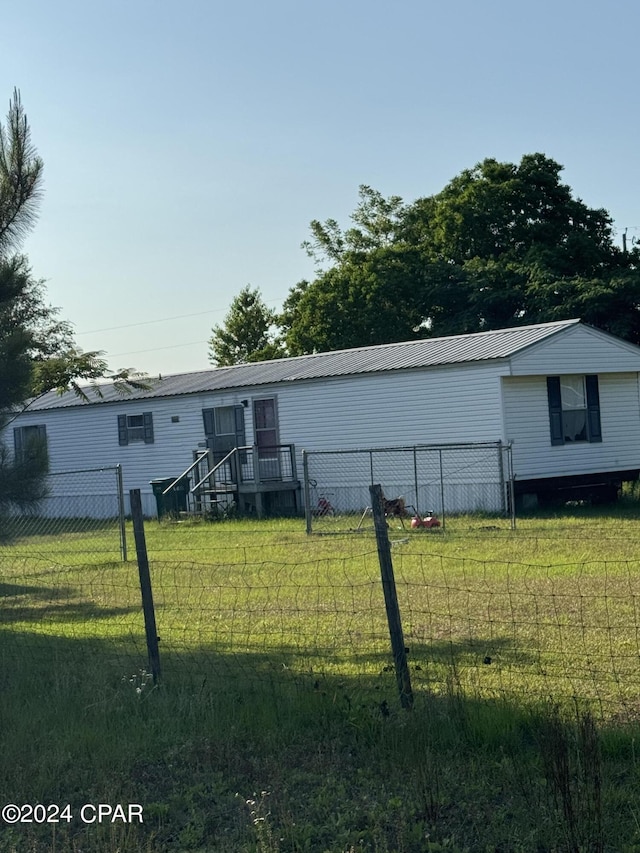 view of front of home with metal roof, a front lawn, and fence