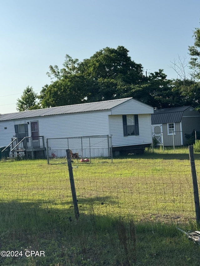 exterior space featuring a storage shed, metal roof, an outbuilding, fence, and a yard