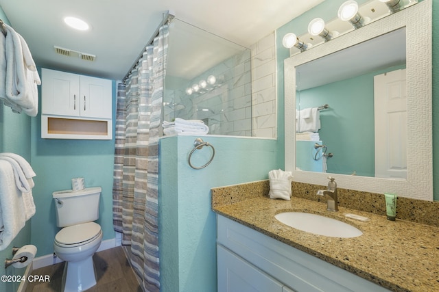 bathroom with wood-type flooring, oversized vanity, and toilet