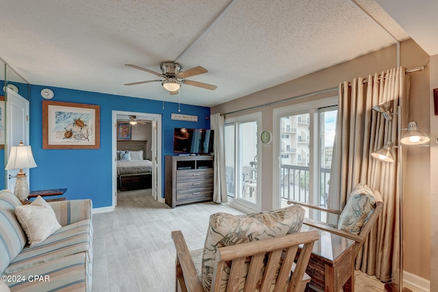 living room with hardwood / wood-style floors, ceiling fan, and a textured ceiling