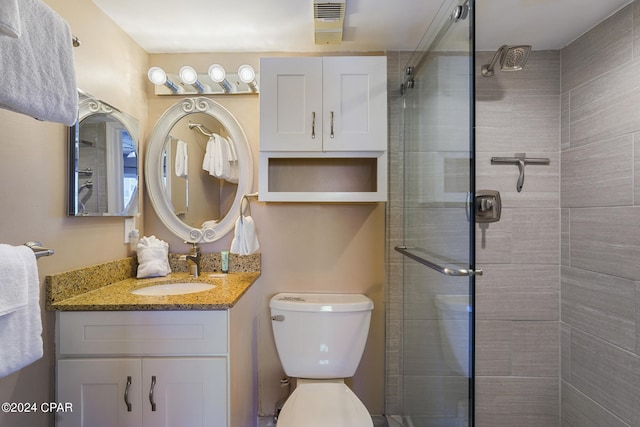 bathroom with a shower with door, toilet, and vanity