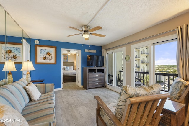 living room with ceiling fan, light wood-type flooring, and a textured ceiling