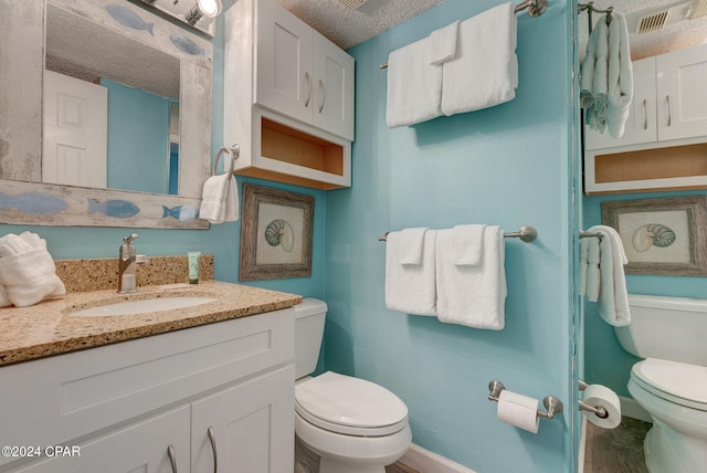 bathroom featuring a textured ceiling, vanity, and toilet