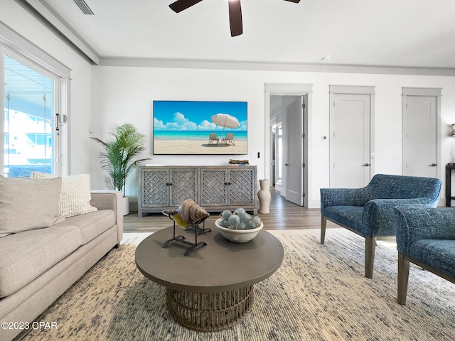 living room with wood-type flooring, ceiling fan, and crown molding