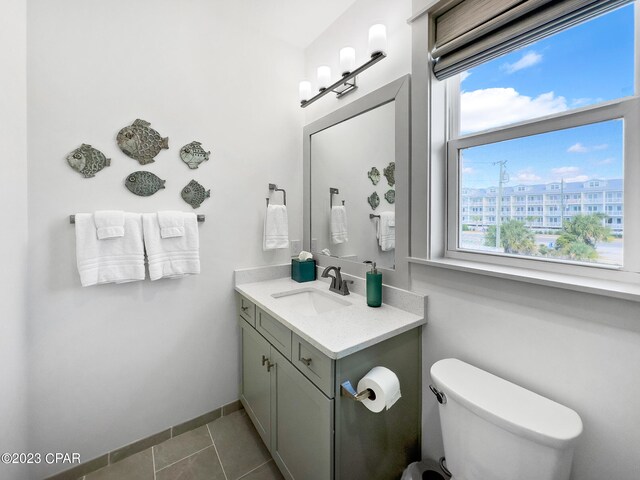 bathroom with tile patterned flooring, vanity, a healthy amount of sunlight, and toilet