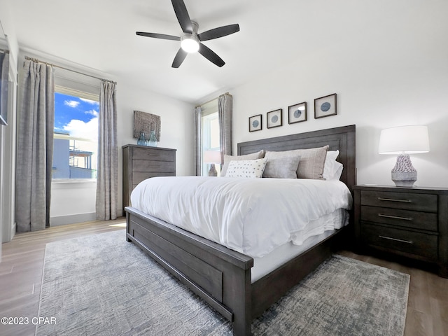 bedroom featuring hardwood / wood-style floors, ceiling fan, and multiple windows