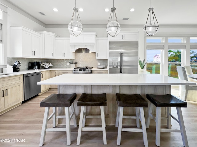 kitchen featuring high end appliances, white cabinets, a center island, and backsplash