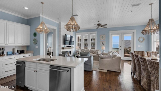 kitchen with sink, dishwasher, hanging light fixtures, white cabinets, and a center island with sink