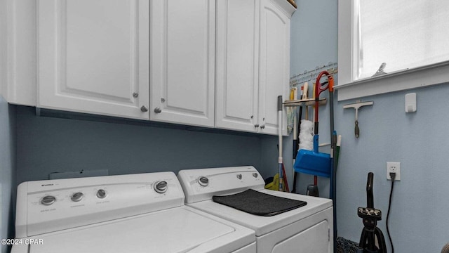 clothes washing area with cabinets and washing machine and dryer