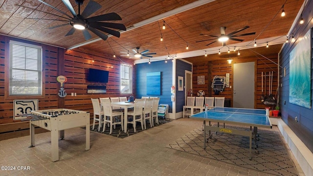 playroom with wooden ceiling, ceiling fan, and wood walls