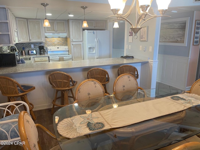 kitchen with kitchen peninsula, range with electric cooktop, white fridge with ice dispenser, a notable chandelier, and hanging light fixtures