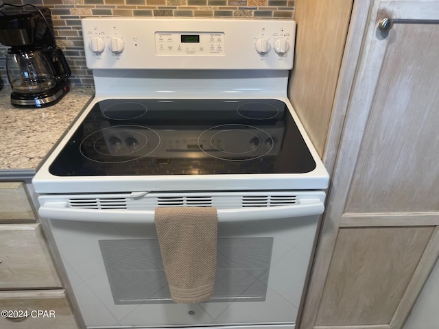 details featuring white range with electric stovetop, decorative backsplash, light stone countertops, and light brown cabinets