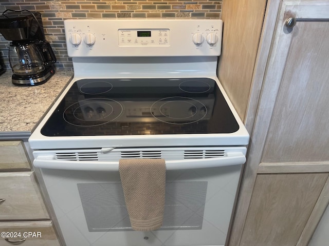 interior details featuring light brown cabinets, light stone counters, and white electric range